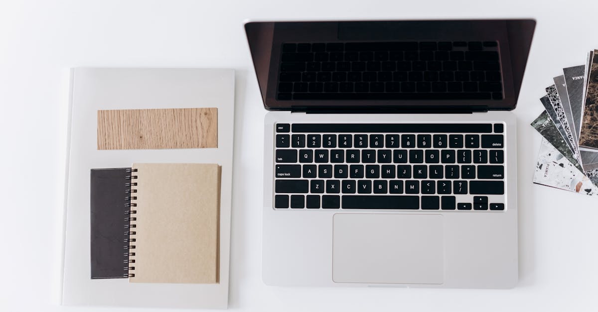 Minimalist workspace setup featuring a laptop, notebooks, and design samples for productivity